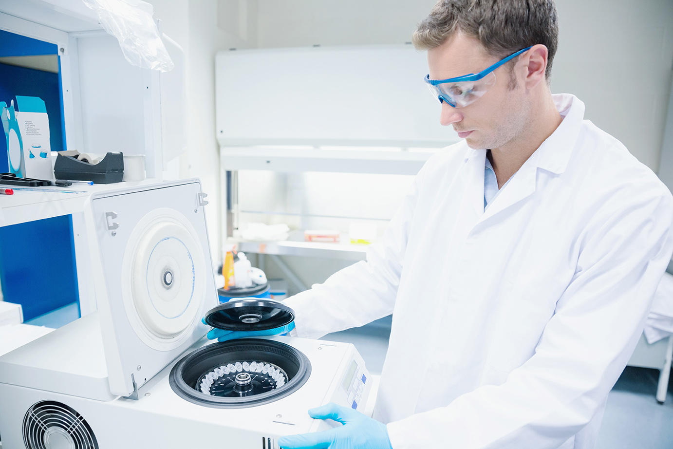 Mężczyzna w laboratorium, ubrany w biały płaszcz stoi przy autoklawie