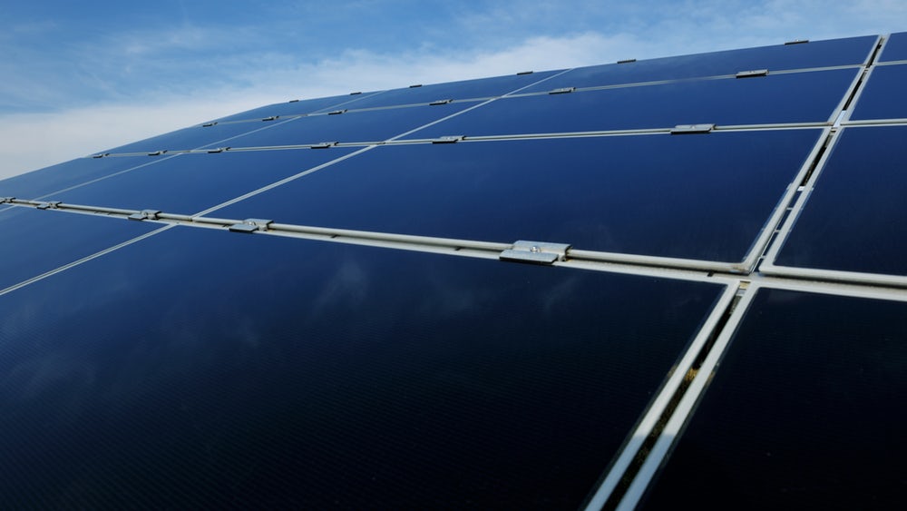 widok na grupę moduł&oacute;w składających się z prostokątnych paneli solarnych. Są pokryte czarnym szkłem i połączone specjalnym systemem montażowym