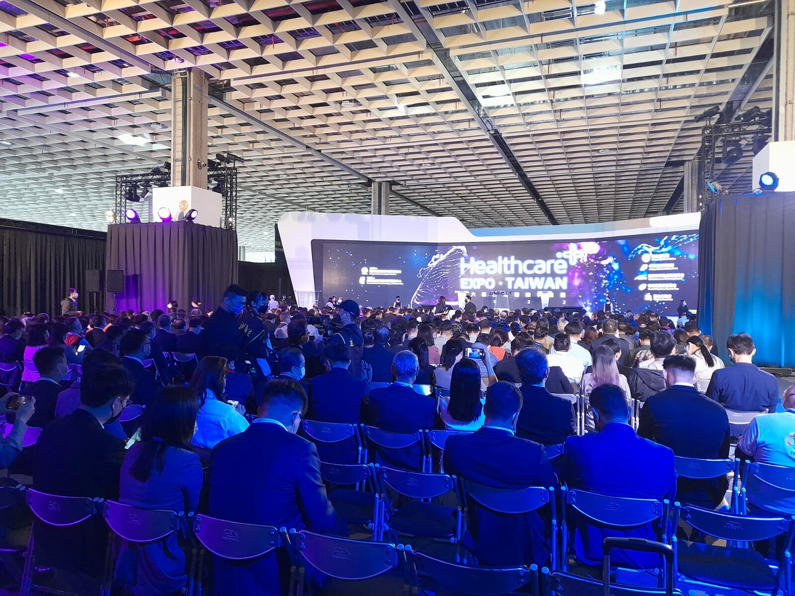 Ludzie siedzą na sali konferencyjnej zwr&oacute;ceni w stronę podium