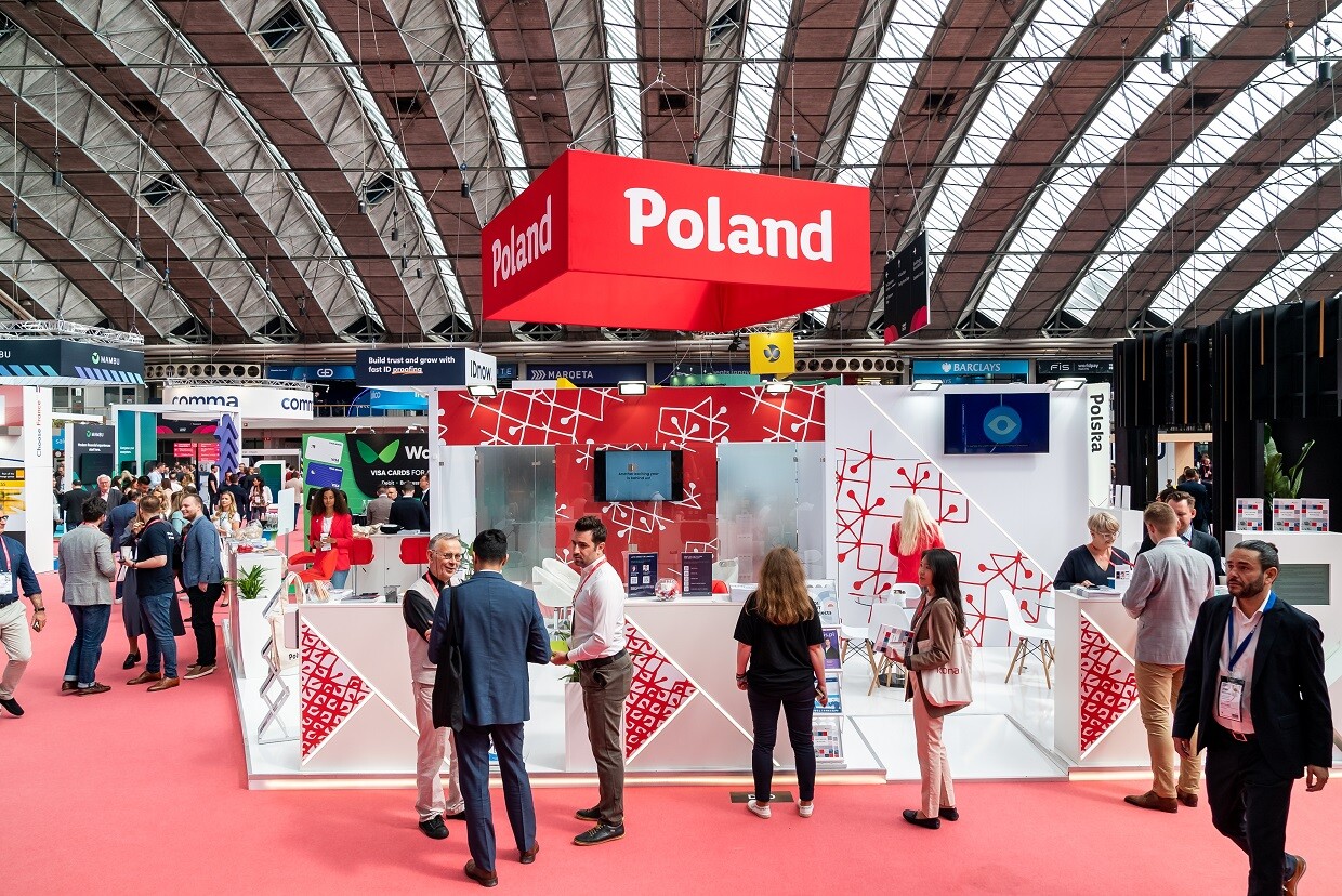 Ludzie w r&oacute;żnym wieku siedzą w hali targowej przy stolikach