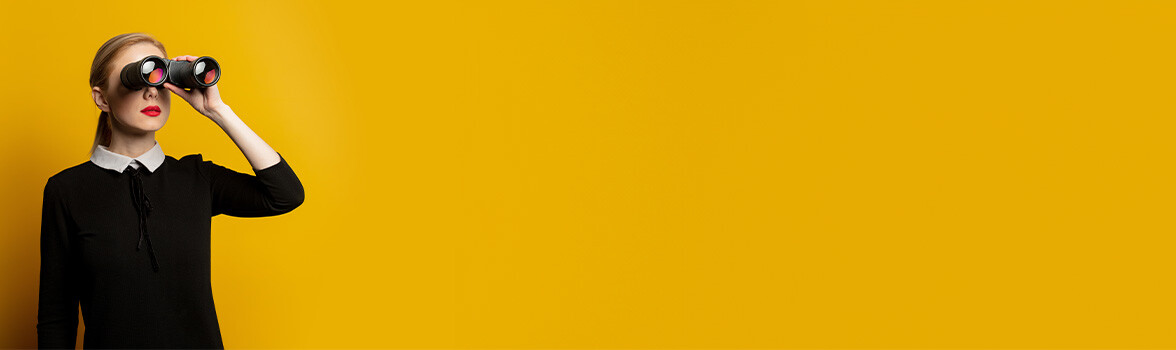 Kobieta z lornetką na ż&oacute;łtym tle